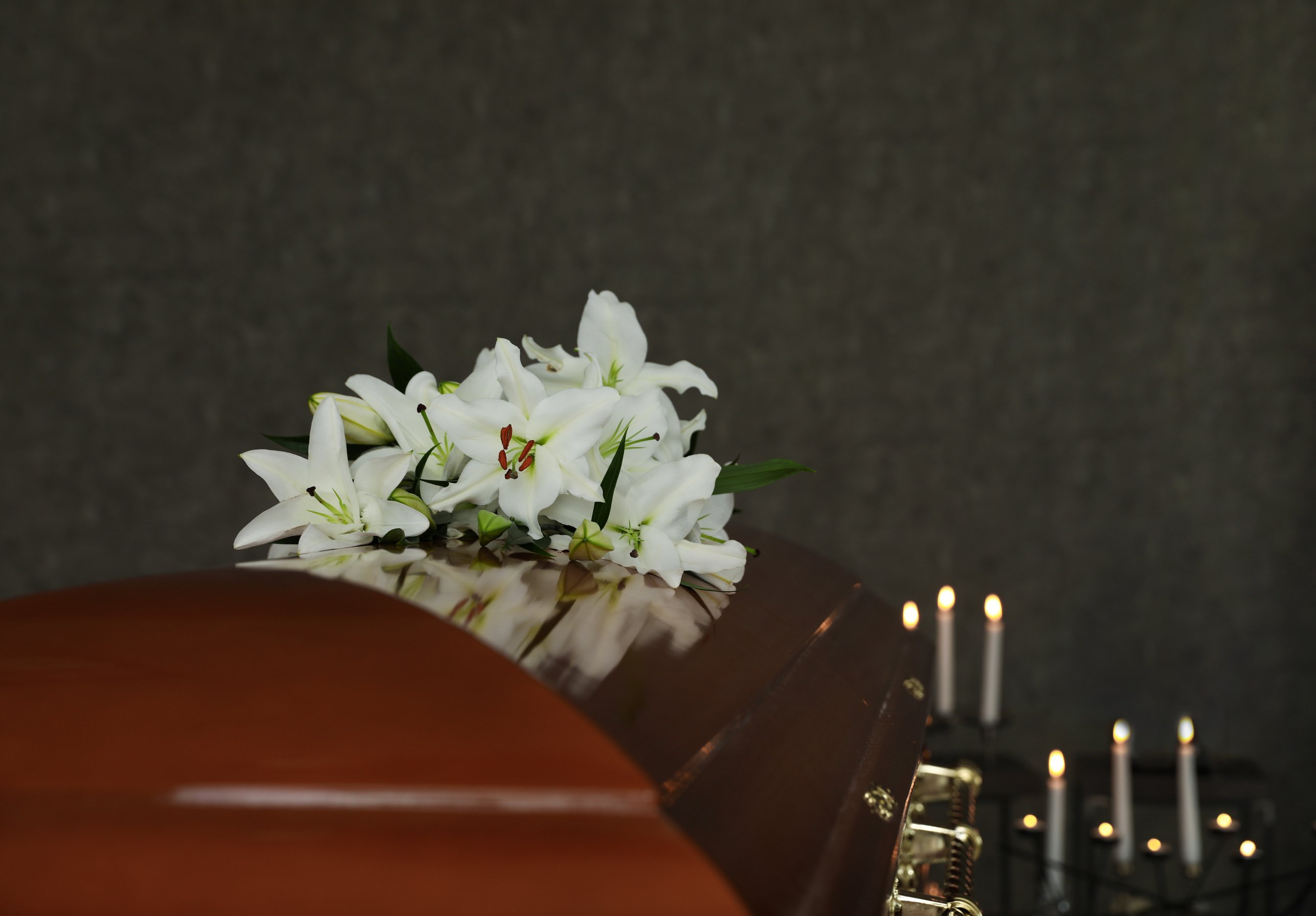 Wooden Casket with White Lilies in Funeral Home